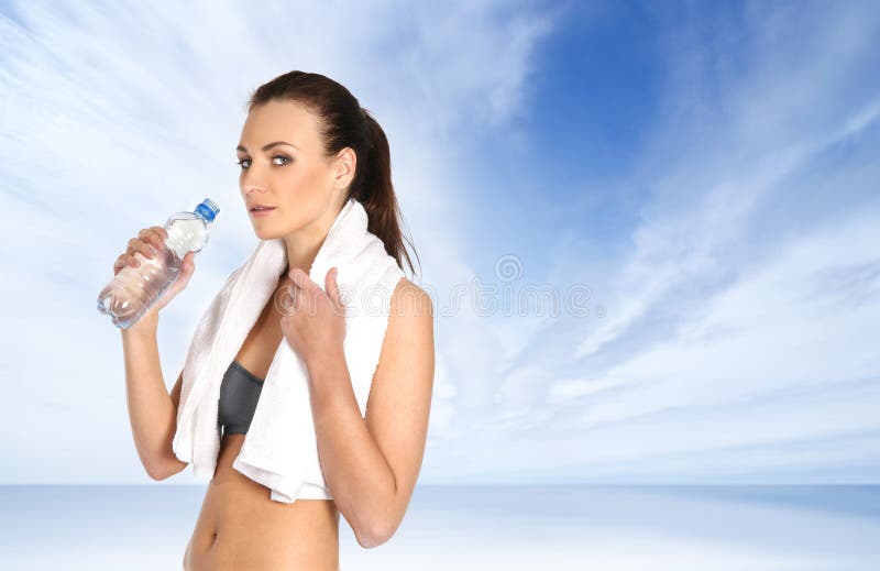 A young and sporty female is drinking water