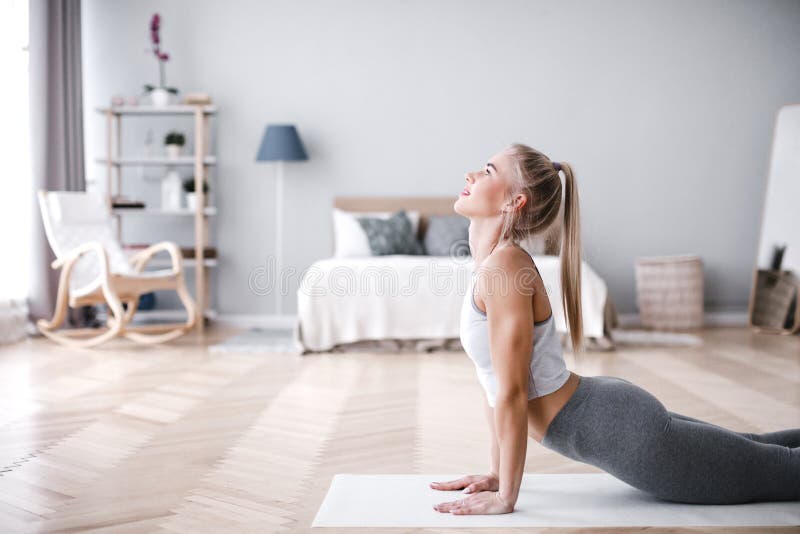 Young sporty woman doing morning exercise in living room on mat