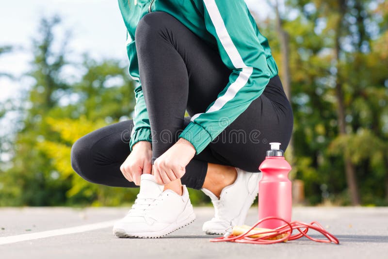 A young sporty woman ties up shoelaces on sneakers. A girl with perfect body doing exercises. stock photo A young sporty woman ties up shoelaces on sneakers. A girl with perfect body doing exercises. stock photo