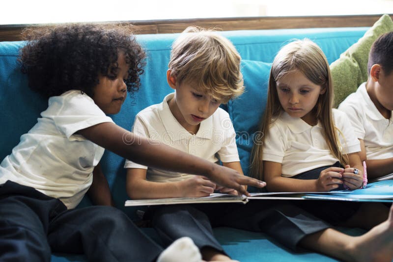 Group of Diverse Young Students Reading Children Story Book Together