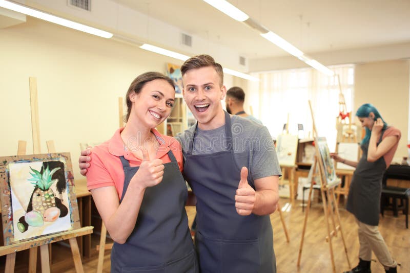 Young students showing thumb-up gesture in art school