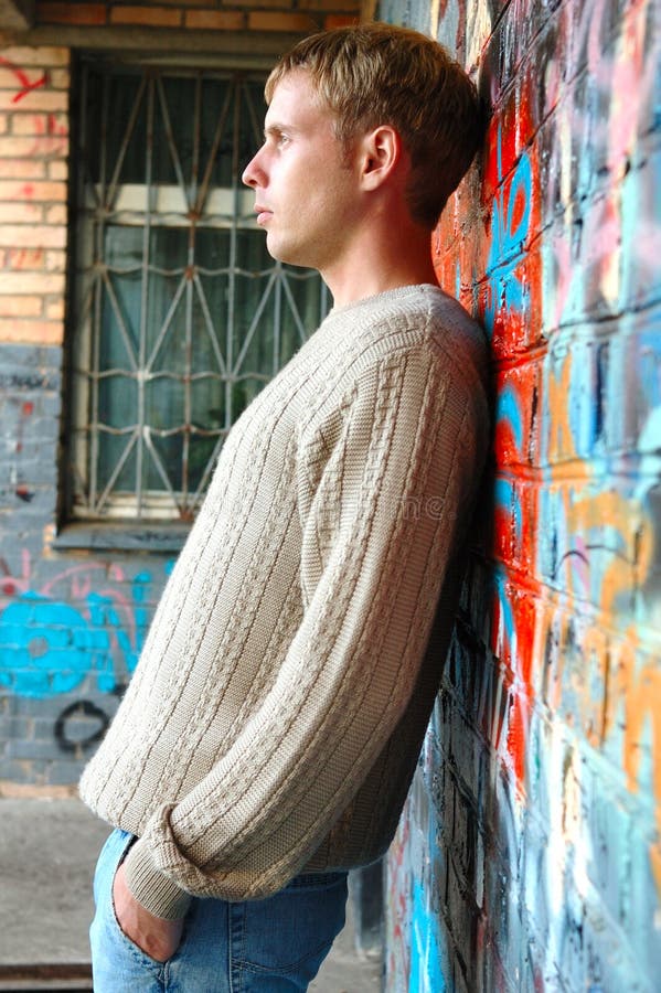 Young stylish man stand near graffiti brick wall.