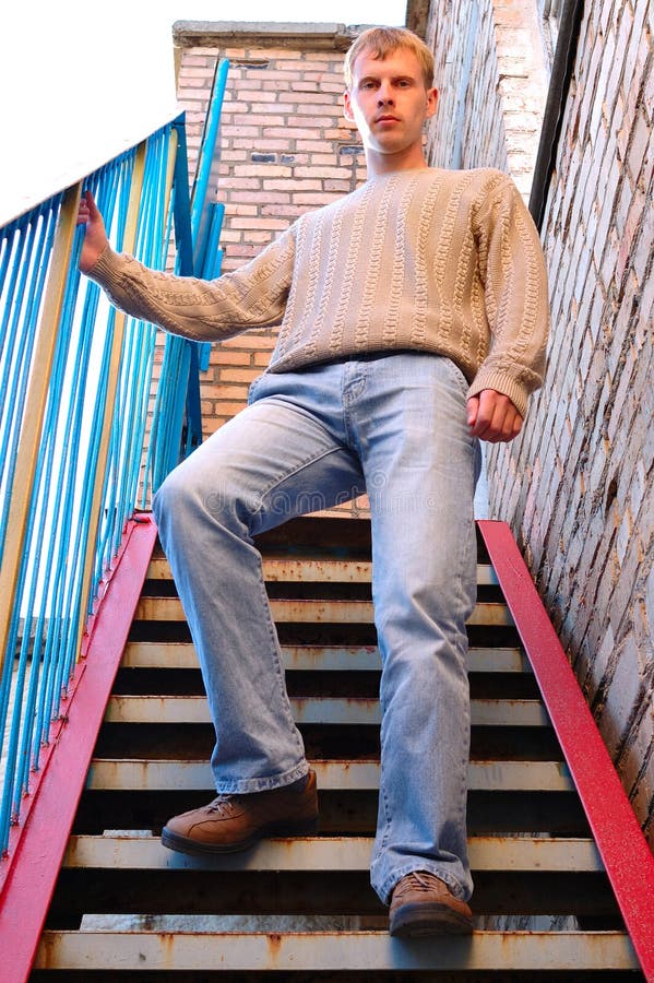 Young stylish man stay on stairs near brick wall.