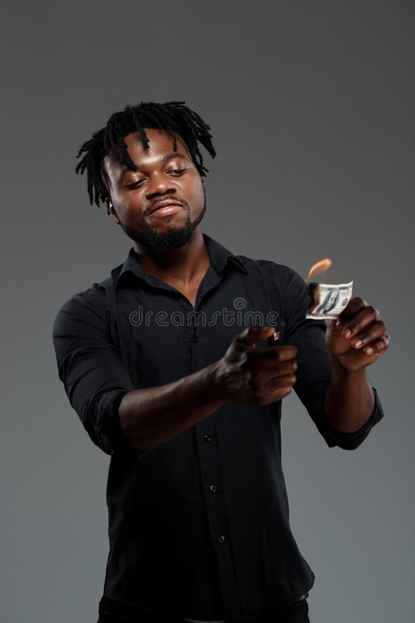 Young successful african businessman burning money over dark background. royalty free stock photo Young successful african businessman burning money over dark background. royalty free stock photo