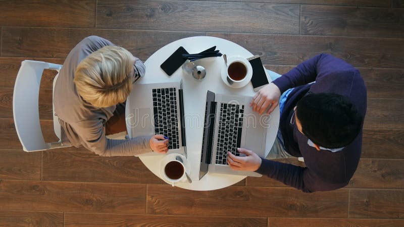 Young successful business couple is discussing documents, drinking coffee and smiling while working in cafe royalty free stock images Young successful business couple is discussing documents, drinking coffee and smiling while working in cafe royalty free stock images