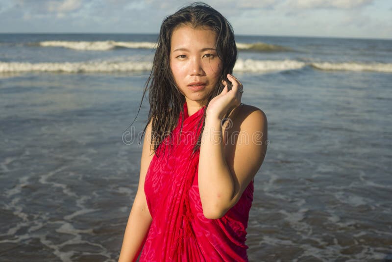 Young sweet and happy Asian Japanese woman in sarong at beautiful beach walking by the sea relaxed and blissful enjoying Summer stock image Young sweet and happy Asian Japanese woman in sarong at beautiful beach walking by the sea relaxed and blissful enjoying Summer stock image