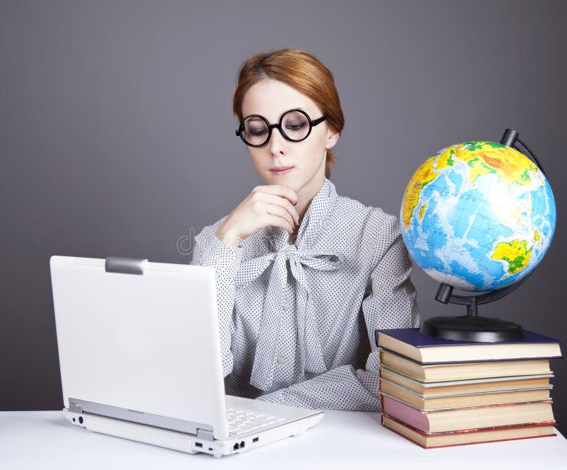 The young teacher with books, globe and notebook.