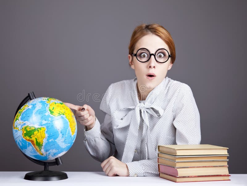 The young teacher in glasses with books and globe