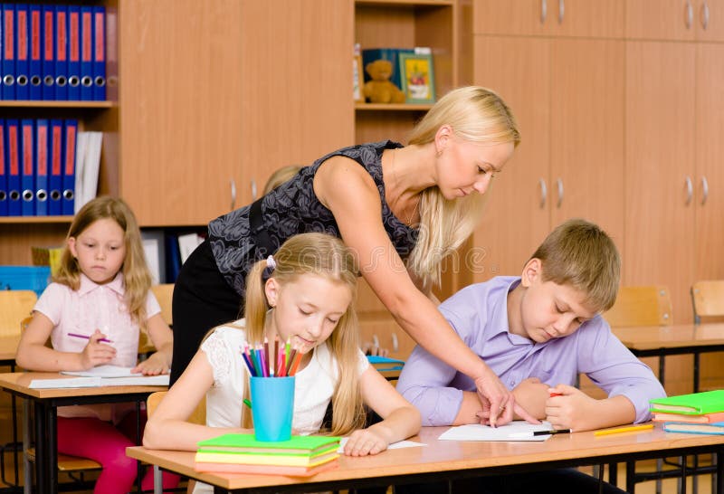 Young teacher helps students of primary school in the exam royalty free stock photos Young teacher helps students of primary school in the exam royalty free stock photos