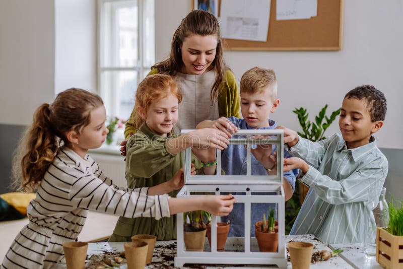 Young Teacher Learning Pupils How To Take Care about Plants. Stock