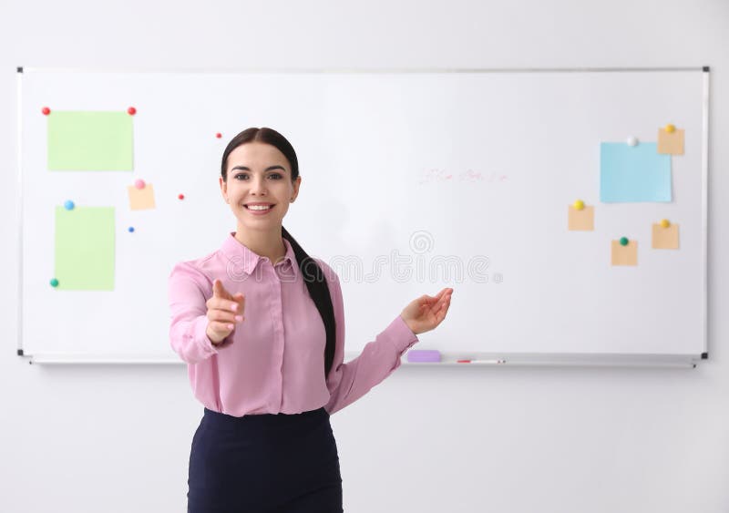 Young Teacher Near Whiteboard in Classroom. Space for Text Stock Photo