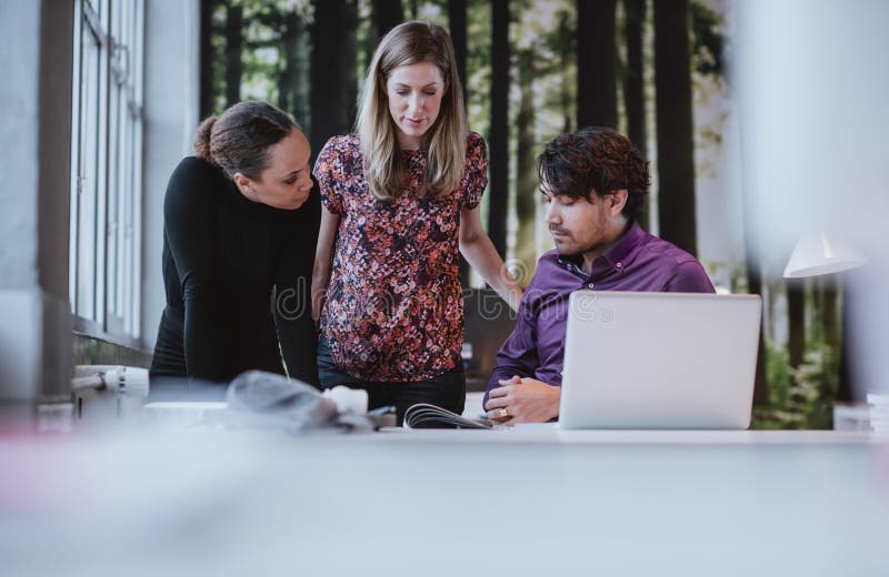 Young team of designers discussing magazine publication royalty free stock photography Young team of designers discussing magazine publication royalty free stock photography