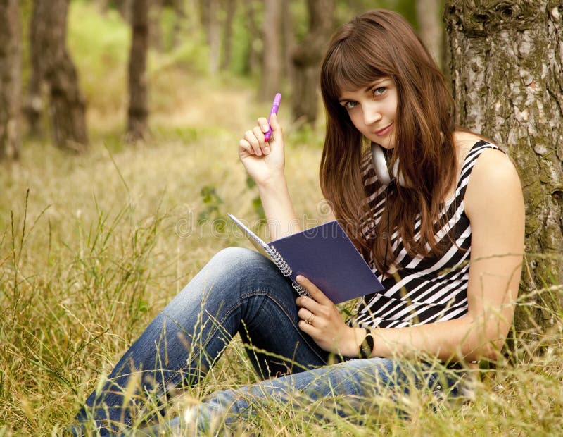 Young teen girl doing homework at the park