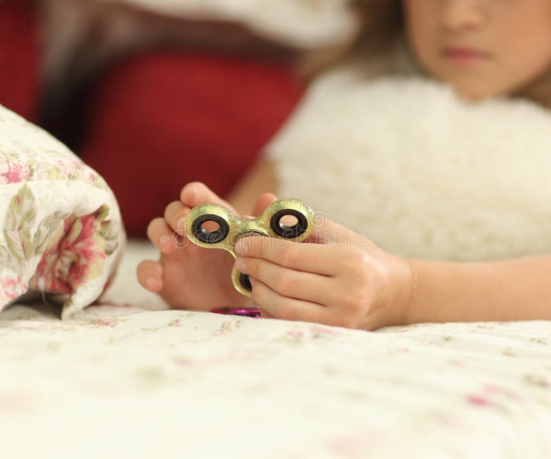 Young teen girl holding popular fidget spinner toy - closeup shot. at home on bed stock images Young teen girl holding popular fidget spinner toy - closeup shot. at home on bed stock images