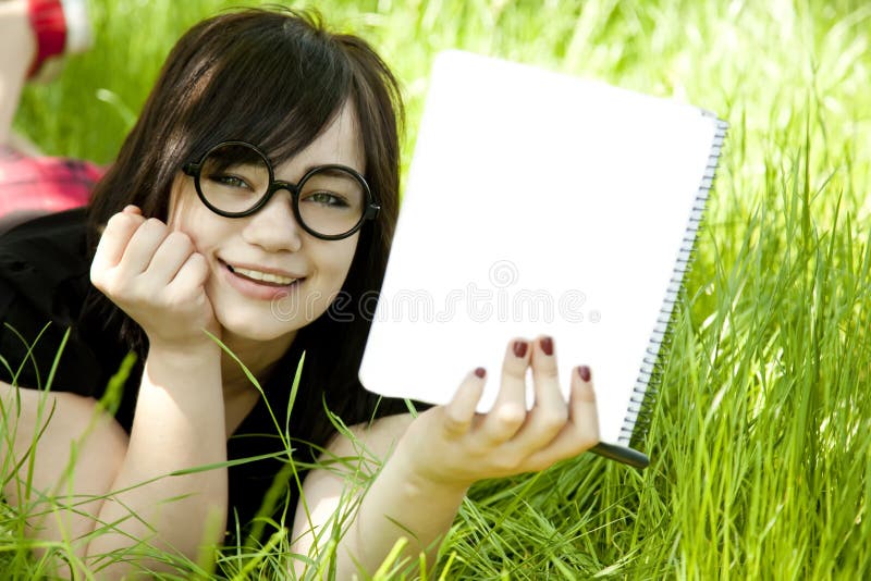 Young teen girl with notebook at green grass