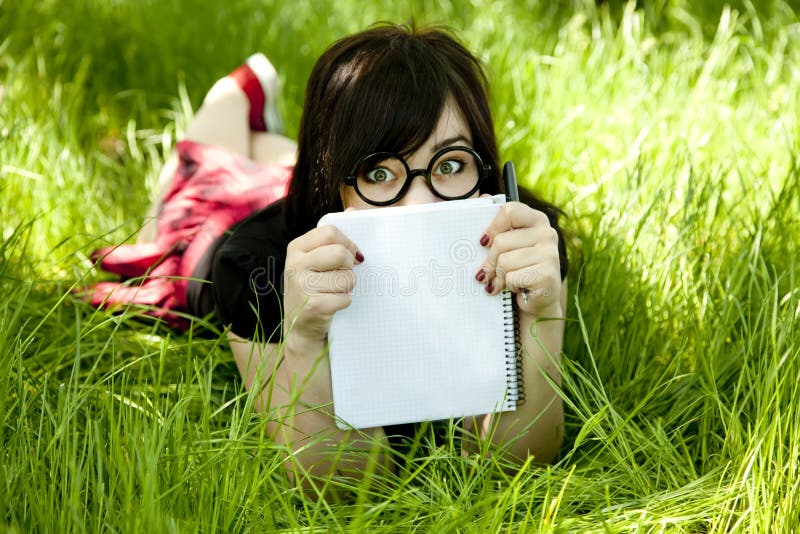 Young teen girl with notebook at green grass