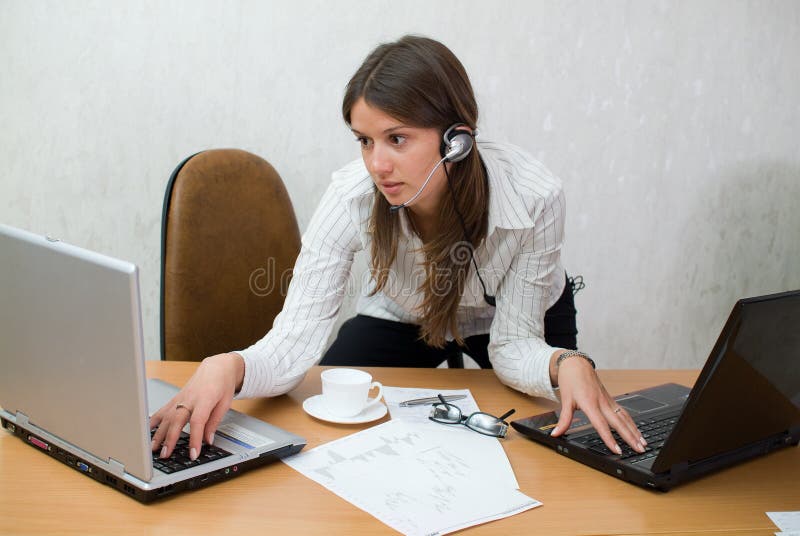 Young teen girl at the office desk with laptops