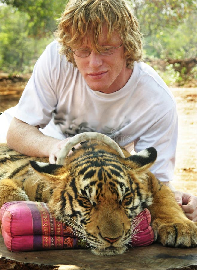 Young man cuddling up close with tiger portrait