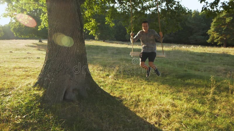 Young teenager boy swinging on rope swing outdoors