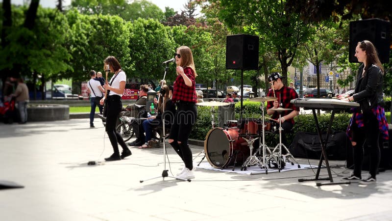 Young teenager girls rock band sing and play guitar in street music day.