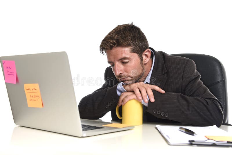 Young tired and wasted businessman working in stress at office laptop computer looking exhausted and overwhelmed by heavy work load sleeping on desk in overwork concept