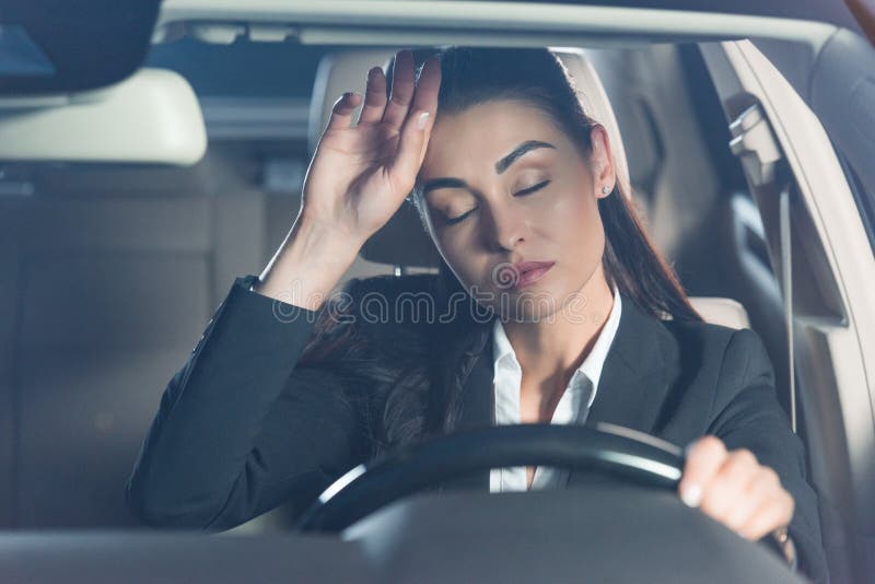 Young tired woman in suit sitting in driver seat and touching stock images Young tired woman in suit sitting in driver seat and touching stock images