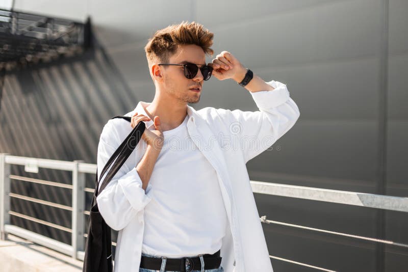 Young Trendy Hipster Man with a Stylish Hairstyle Straightens Black Sunglasses. Handsome Modern Guy in Fashionable White Clothes Stock Photo - Image of menswear, city: 154112266 Young Trendy Hipster Man with a Stylish Hairstyle Straightens Black Sunglasses. Handsome Modern Guy in Fashionable White Clothes Stock Photo - Image of menswear, city: 154112266