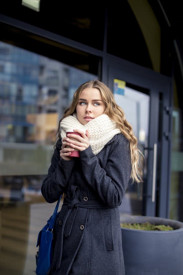 Young trendy woman drinking take away coffee and walking after shopping in an urban city.