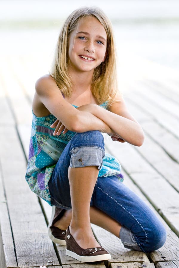 Young tween girl kneeling on a dock.