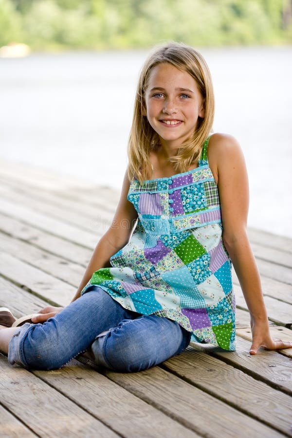 Young tween girl sitting on a pier