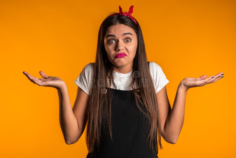 Young unsure girl shrugs her arms, makes gesture of I don`t know, care