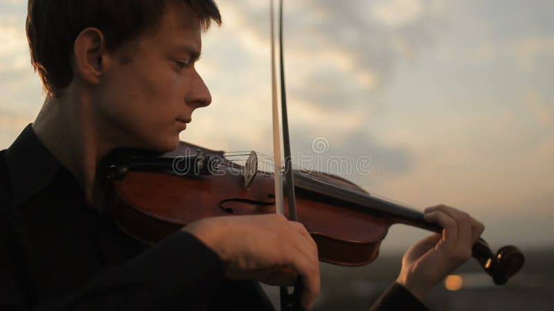 Young violinist playing at sunset. Close-up of strings and bow