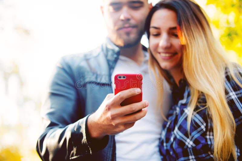 Young white couple using mobile phone in a park