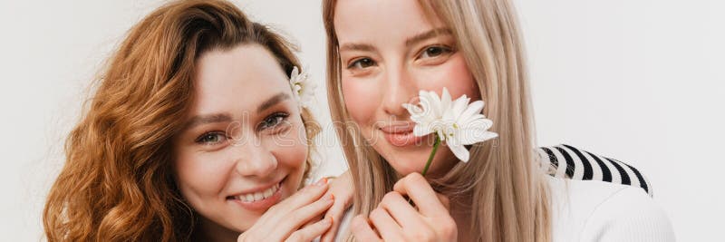 Young white two women hugging and smiling while posing with flowers stock images