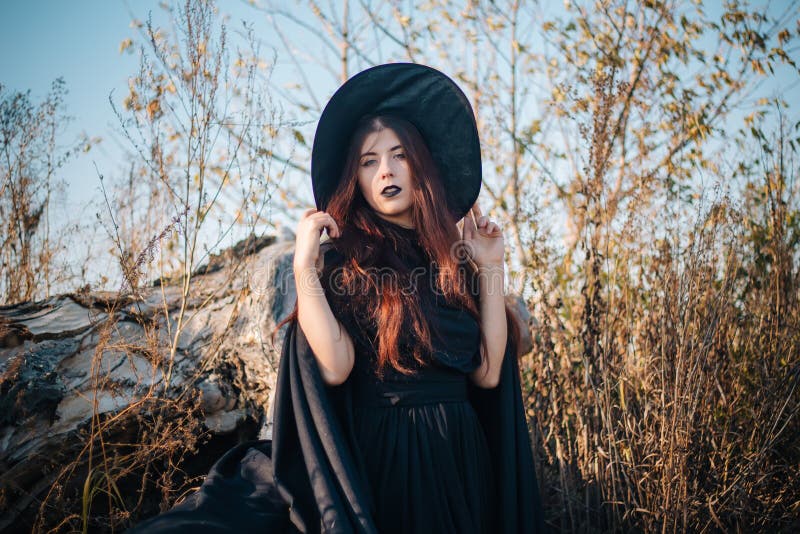 A Young Witch with Pale Skin and Black Lips, Wearing a Black Hat, Dress ...
