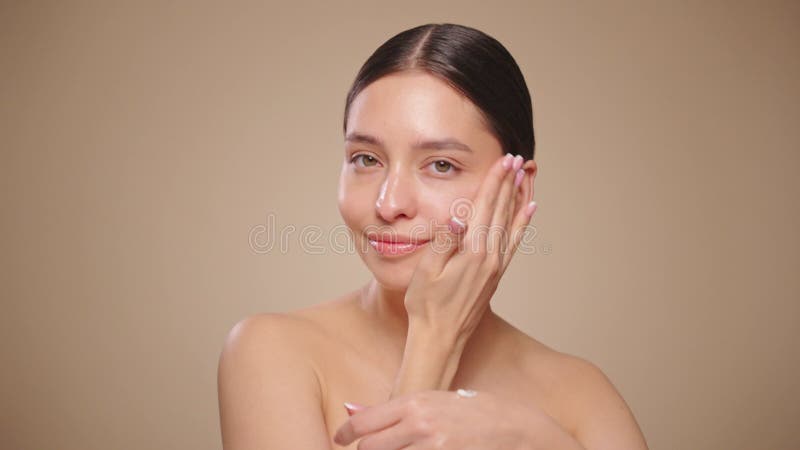 Young woman applies skin care cream to her face