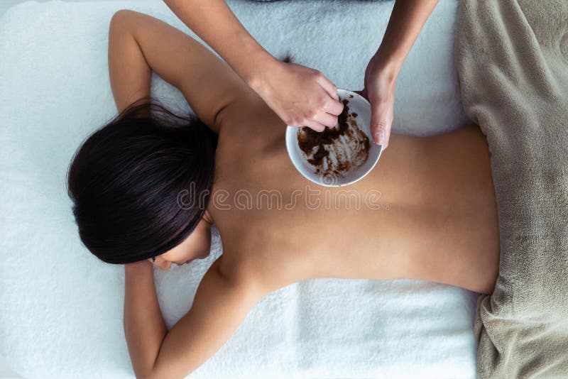 Young woman applying chocolate cream with natural ingredients for body treatment to a pretty woman on the spa center royalty free stock photo Young woman applying chocolate cream with natural ingredients for body treatment to a pretty woman on the spa center royalty free stock photo