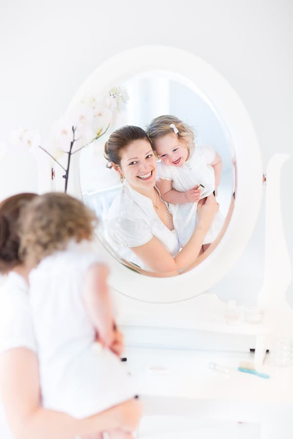 Young woman applying make up with her daughter