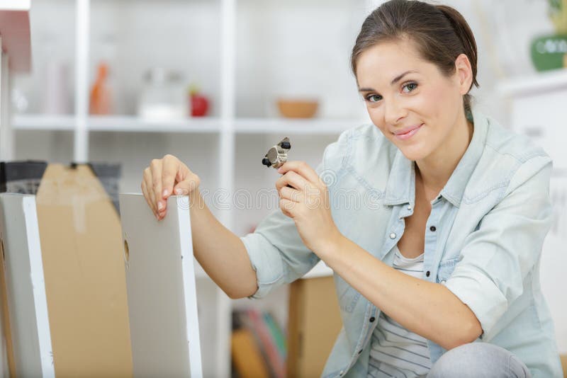 Young woman assembling furniture in new apartment