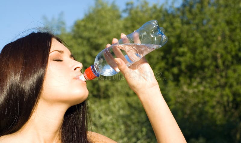 A young woman athlete drinking after a long run