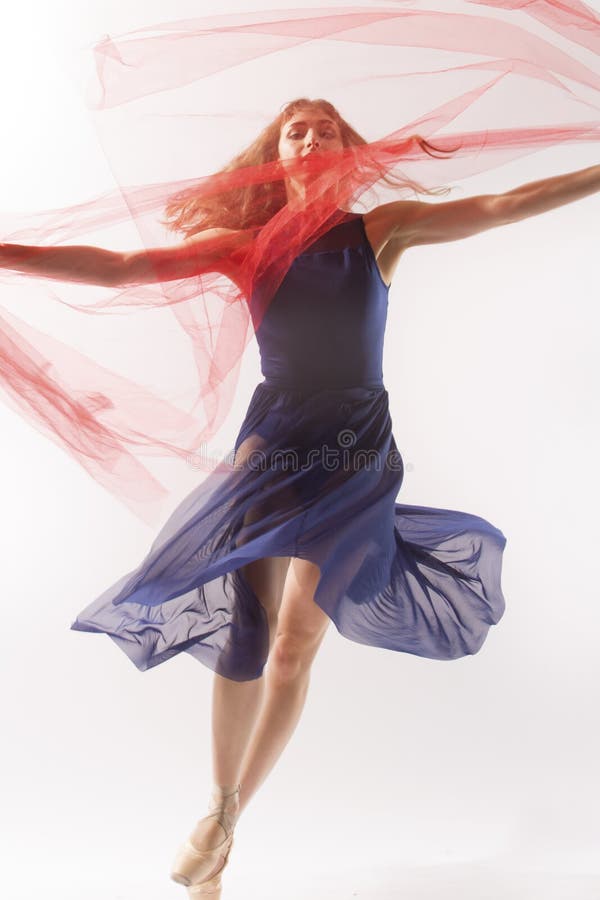Young woman ballet dancer in pointe shoes,blue leotard and skirt, dancing in the studio with a red fabric, all against a white background. Young woman ballet dancer in pointe shoes,blue leotard and skirt, dancing in the studio with a red fabric, all against a white background