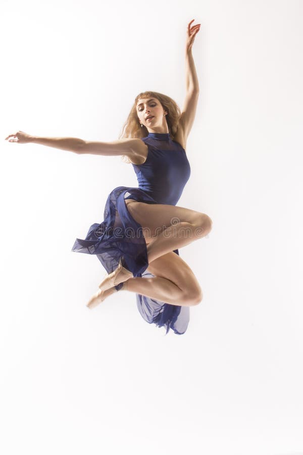 Young woman ballet dancer in pointe shoes,blue leotard and skirt, leaping in the studio against a white background. Young woman ballet dancer in pointe shoes,blue leotard and skirt, leaping in the studio against a white background