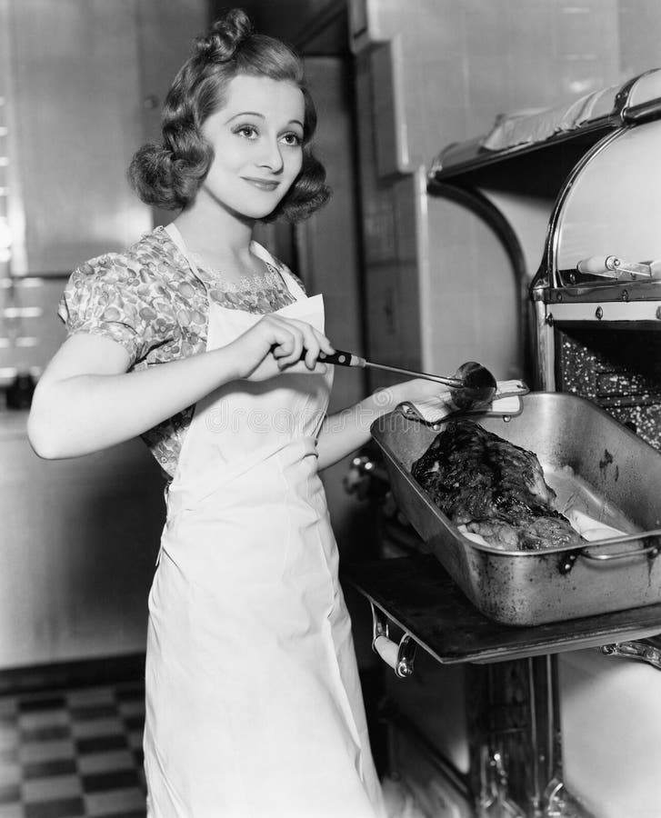 Young woman basting a goose in the kitchen royalty free stock photo Young woman basting a goose in the kitchen royalty free stock photo