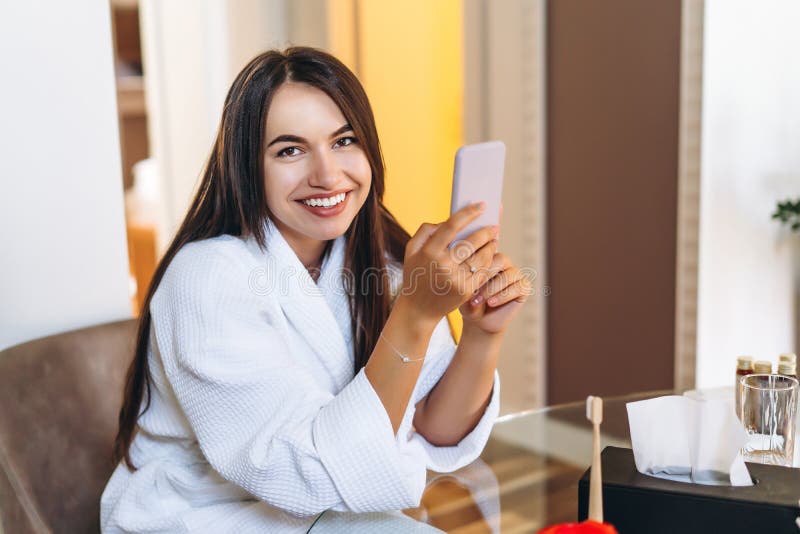 Young Woman in Bathrobe in Hotel Room Using Mobile Phone Stock Image