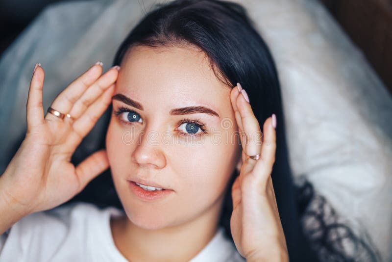 Young woman with beautiful eyebrows after procedure permanent make-up in salon  closeup photo