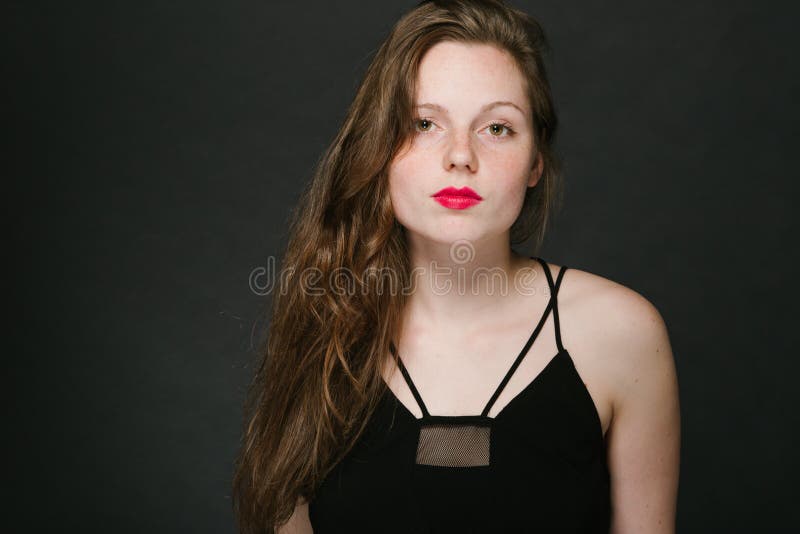 Young woman beautiful portrait with red lips and freckles in classic dress on black baackground