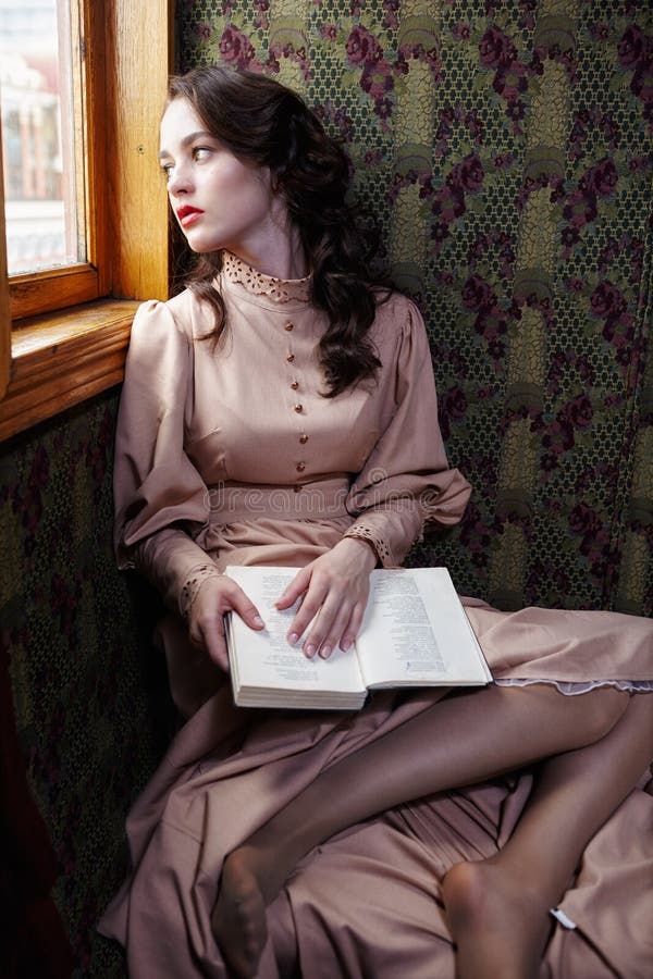 Young woman in beige vintage dress of early 20th century reading royalty free stock photo Young woman in beige vintage dress of early 20th century reading royalty free stock photo