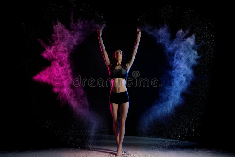 Attractive woman standing in colorful smoke with hands up