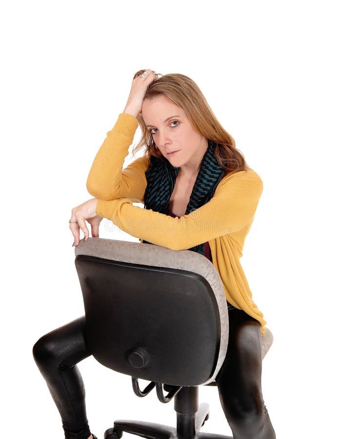 A serious looking woman sitting backwards on office chair. 