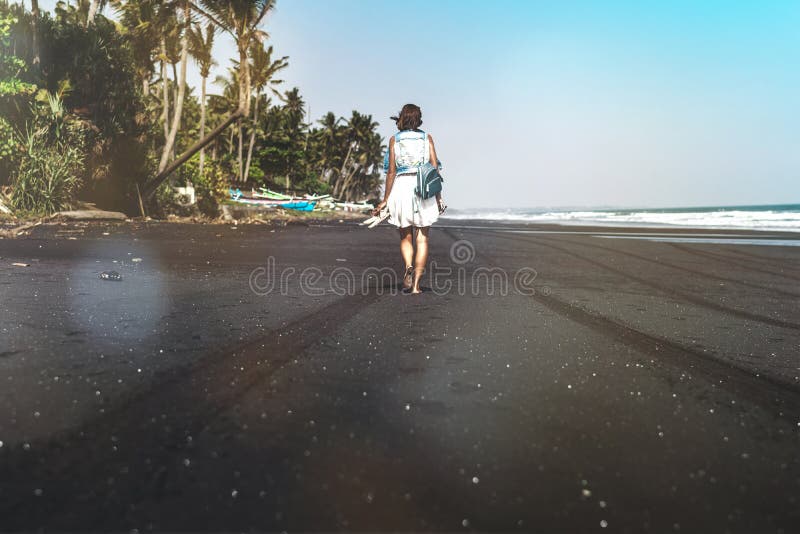 Young woman on a black sand beach, Bali island. Beauty, body.